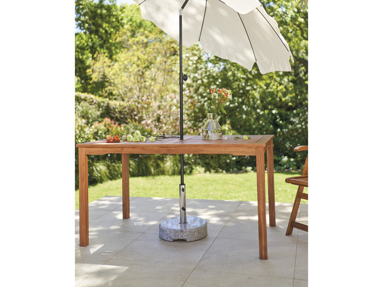 Dřevěný stůl s deštníkem na terase.