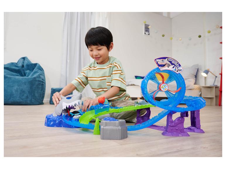 Chlapec si hraje s herní sadou Hot Wheels Shark Cyclone na podlaze.