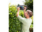 Muž stříhá živý plot elektrickými nůžkami na živý plot.