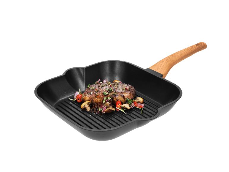 Grilovaný steak se zeleninou v černé čtvercové grilovací pánvi s dřevěnou rukojetí.