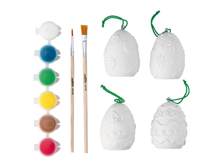 Bílá velikonoční vajíčka s různými vzory k malování barvami a štětci Crelanda.