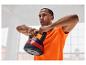 Muž v oranžovém tričku drží 10kg kettlebell.