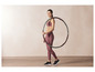 Žena v sportovním oblečení drží fitness kruh.