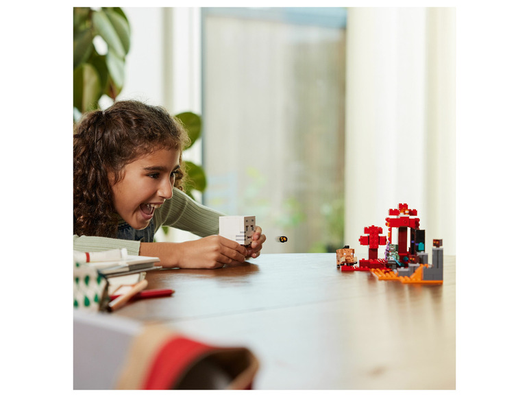 Dívka si hraje s LEGO Minecraft figurkami, včetně kostry a portálu do Netheru.