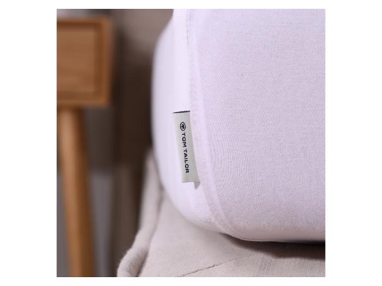 Bílý polštář Tom Tailor se štítkem v interiéru.
