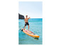Muž stojí na nafukovacím paddleboardu Aqua Marina v oranžové a červené barvě v moři.