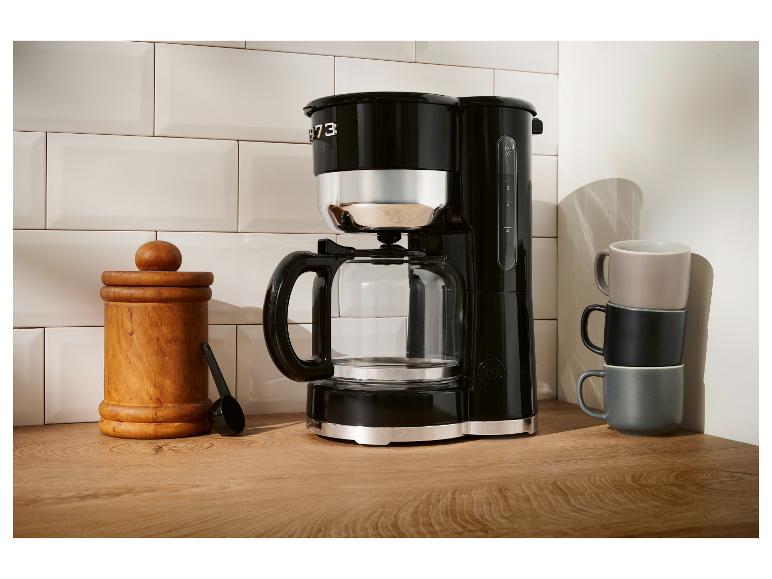 Černý kávovar Smeg na dřevěné desce.