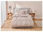 Ložní souprava s květinovým vzorem v béžové a bílé barvě na posteli.