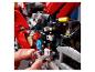 Osoba sestavuje červenou motorku LEGO Technic s viditelnými převody.