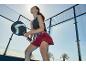 Žena hrající padel s raketou, oblečená ve sportovním topu a sukni-šortkách.