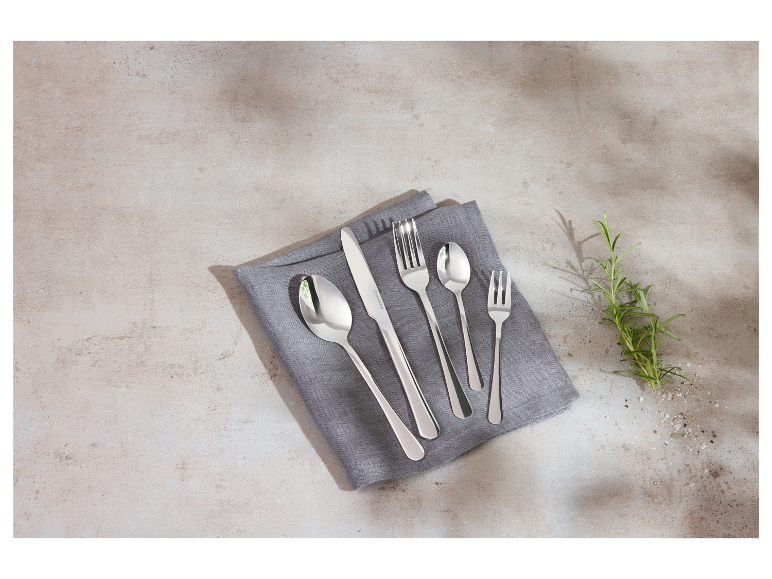 Souprava příborů na šedé látkové ubrousku.