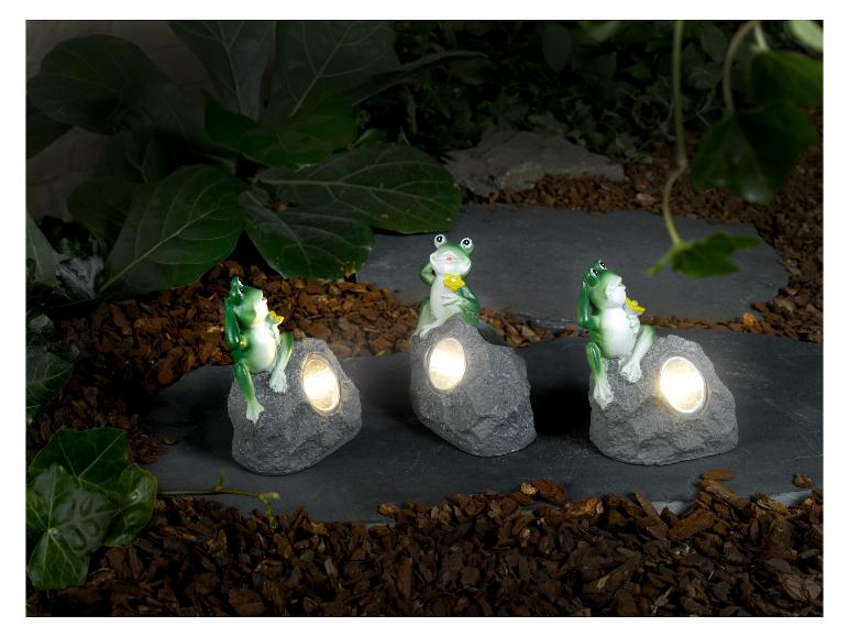 Tři solární lampy ve tvaru žab na dekorativních kamenech do zahrady.
