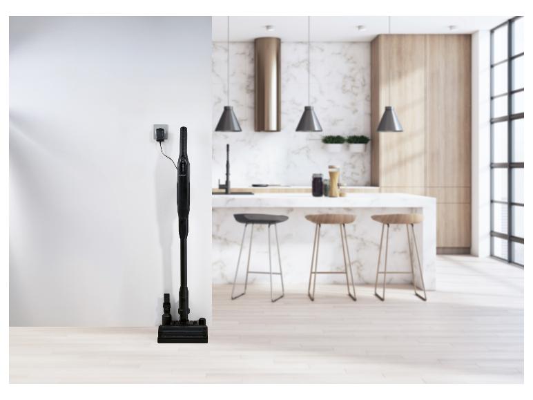 Bezdrátový vysavač SilverCrest se nabíjí v moderní kuchyni.