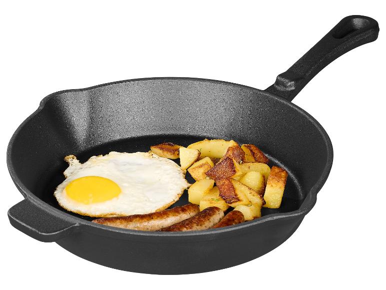 Smažená vejce, klobásy a brambory na litinové pánvi.