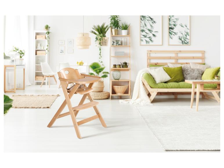 Dřevěná jídelní židlička ve světlém, rostlinami plném obývacím pokoji se zelenou pohovkou