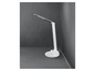 Bílá stolní lampa s flexibilním ramenem v rohu na šedé podlaze.