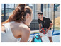 Dvě osoby s raketami na padel na kurtu.