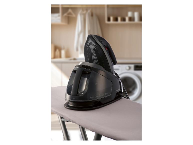 Parní žehlička na žehlicím prkně v prádelně.