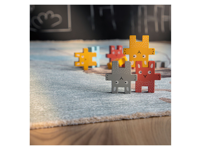 Dřevěné puzzle s motivy zvířátek na koberci.