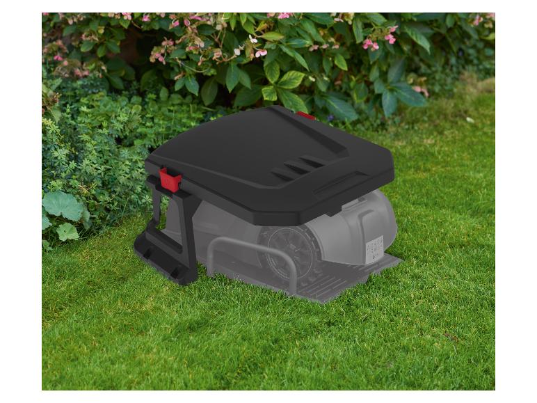 Robotická sekačka s nabíjecí stanicí na zelené trávě před keři.