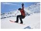 Snowboardista v červeno-černé bundě, černých kalhotách, helmě a brýlích, ve vzduchu.