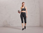Žena v sportovním oblečení drží šedý fitness míč značky Grit.