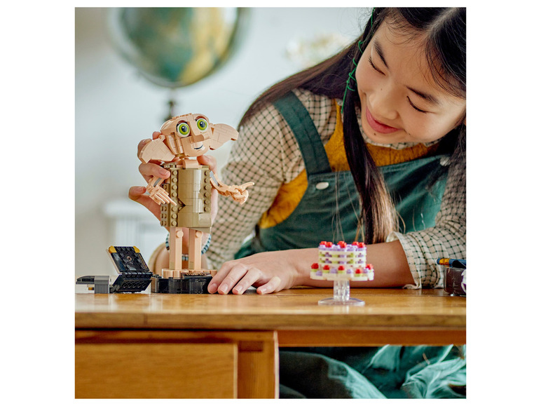 Dívka se dívá na LEGO figurku Dobbyho z Harryho Pottera.
