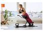 Žena cvičící na posilovacím stroji s 6kg kettlebellem, 8kg kettlebell na podlaze.
