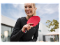 Žena s úsměvem drží červenou raketu na stolní tenis.
