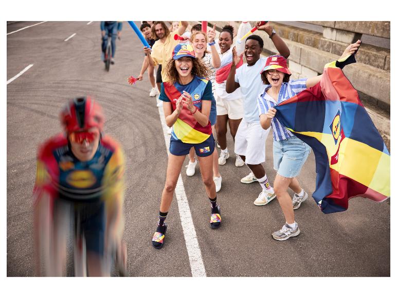 Cyklisté a jásající fanoušci v barevném sportovním oblečení, čepicích a ponožkách s vlajkou.
