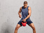 Muž v sportovním oblečení s červenou kettlebell od Crivit.