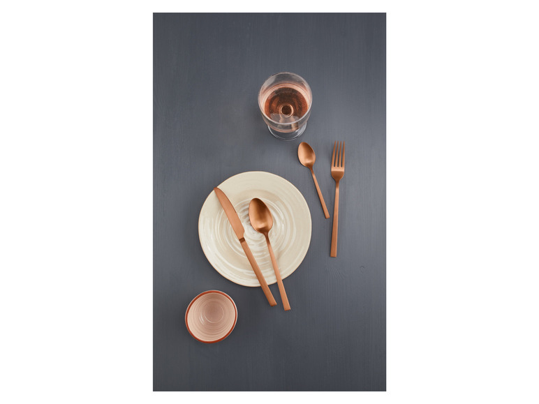 Talíř s příborem a sklenkou růžového vína.