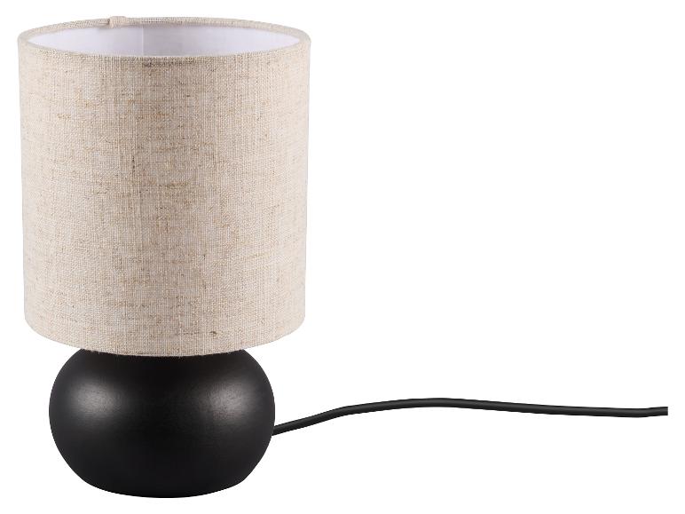 Stolní lampa s černou kulovou základnou a béžovým válcovým látkovým stínidlem.