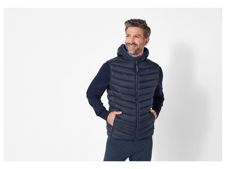 Muž v tmavě modré prošívané vestě s kapucí od Le Coq Sportif.