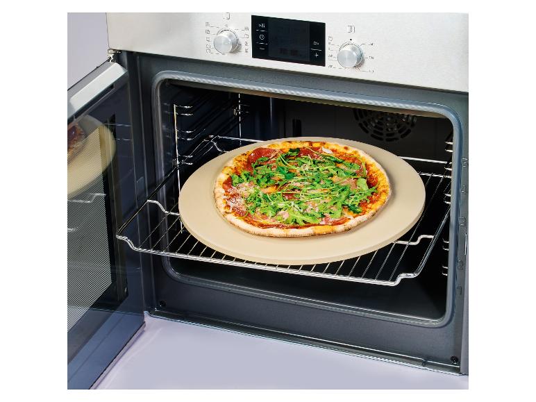 Pizza s rukolou a prosciuttem na pizza kameni v otevřené troubě.