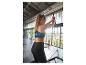 Žena v černém sportovním oblečení cvičící na fitness stroji.