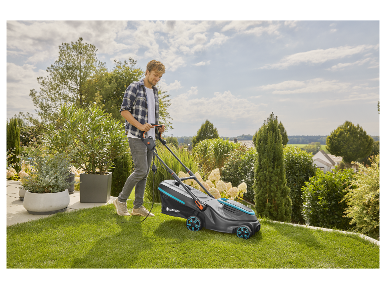 Muž používá elektrickou sekačku Gardena na své zahradě.