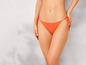 Žena nosí oranžové kalhotky z bikin.