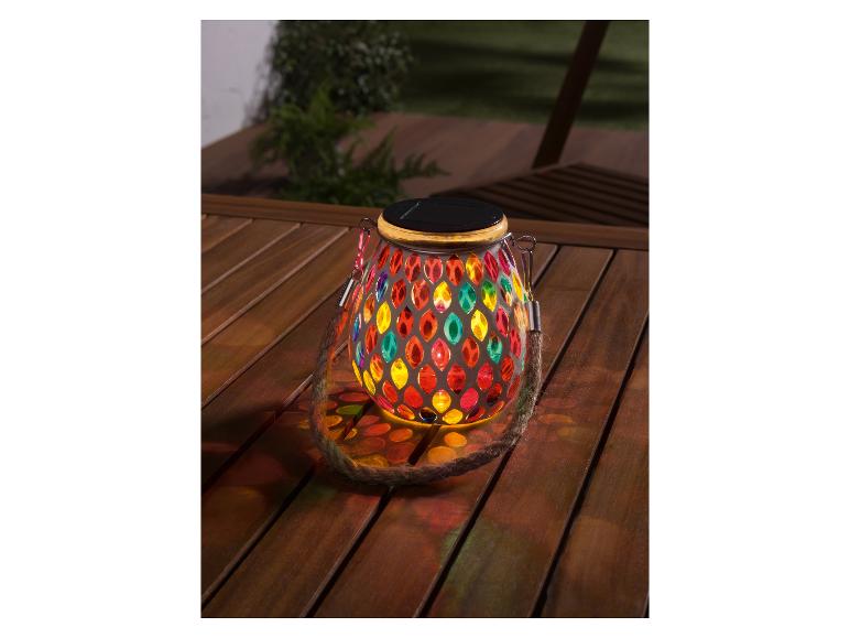 Barevná solární lampa ze skla na dřevěném stole.
