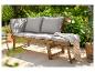 Dřevěná zahradní lavice s šedými polštáři na terase, obklopená zelení