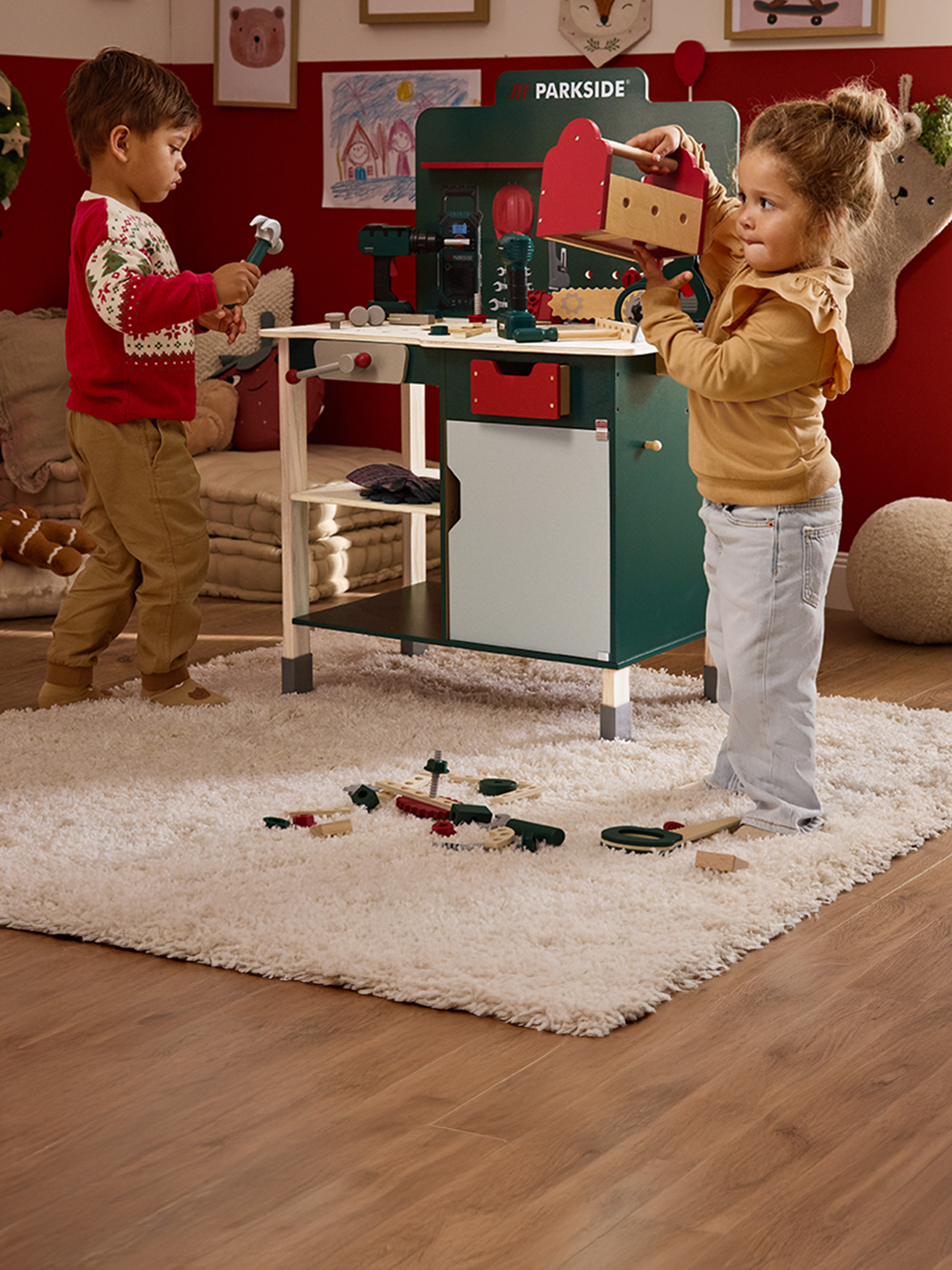 Dvě děti si hrají s hračkovým pracovním stolem Parkside a dřevěným nářadím.