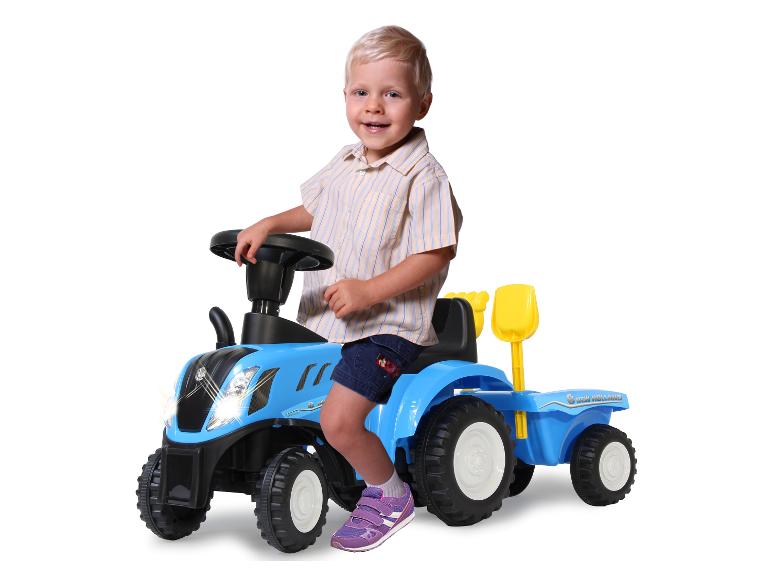 Batole sedí na modrém dětském traktoru New Holland.