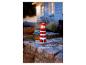 Světelná lampa ve tvaru červenobílého majáku na zahradě