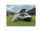 Bílý Volkswagen Transporter s vyklápěcí střechou a rozloženým markýzou na kempu.