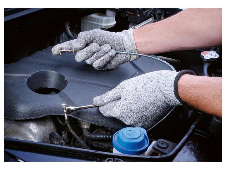 Mechanik používá nástroj na odstranění sponek v motorovém prostoru automobilu.
