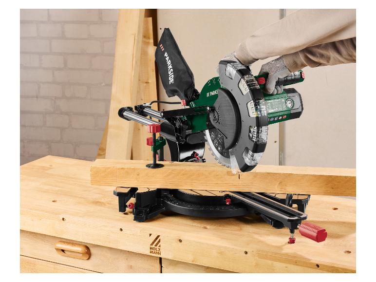 Osoba řeže dřevo s pokosovou pilou na pracovním stole.