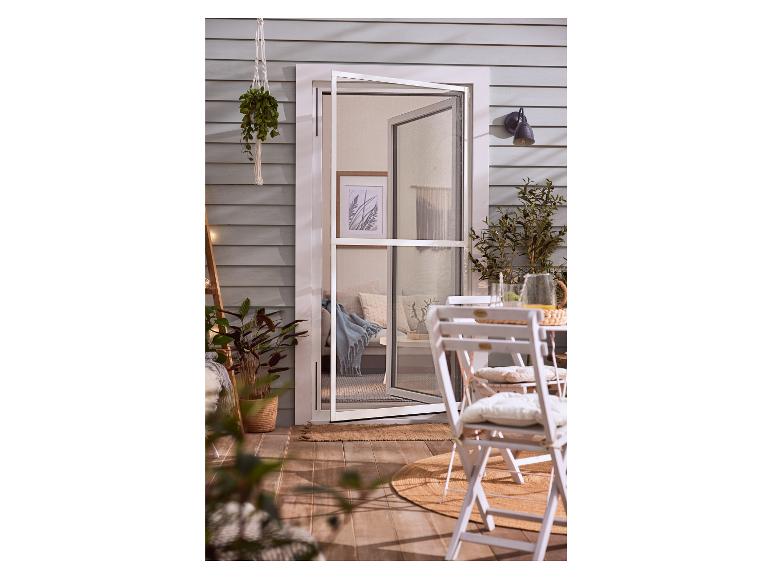 Bílé dveře s moskytiérou, dvě židle a kulatý koberec na terase.
