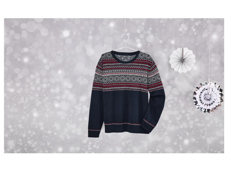 Tmavě modrý svetr se skandinávským vzorem visí na stříbrném pozadí.