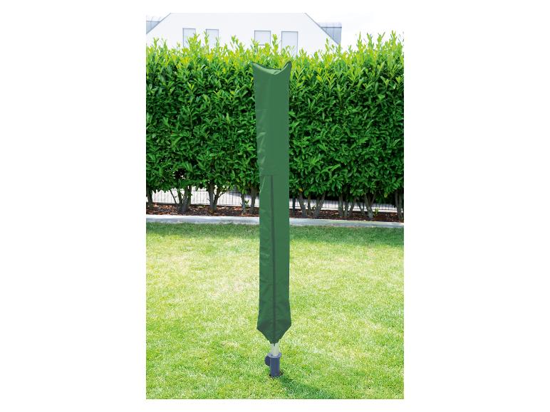 Zelený obal na otočný sušák na prádlo v zahradě s živým plotem a domem v pozadí.