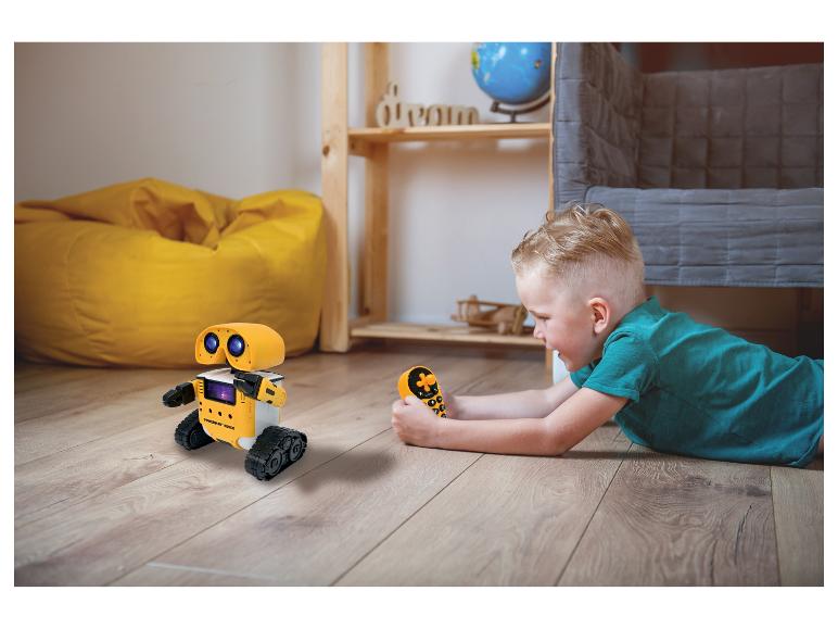 Chlapec si hraje se žlutým dálkově ovládaným robotem na podlaze.